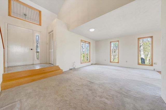 entryway featuring a wealth of natural light, a towering ceiling, visible vents, and carpet floors