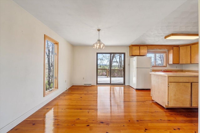 kitchen with light wood-type flooring, freestanding refrigerator, and a wealth of natural light