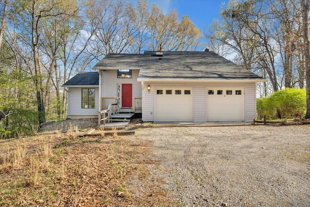 tri-level home with a garage and roof with shingles