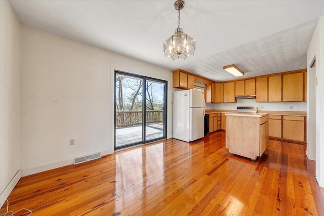 kitchen featuring visible vents, a notable chandelier, light countertops, freestanding refrigerator, and under cabinet range hood