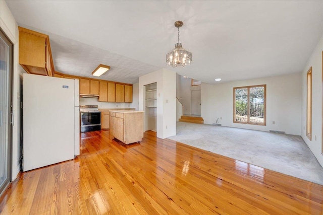 kitchen with electric range oven, open floor plan, light countertops, freestanding refrigerator, and a chandelier