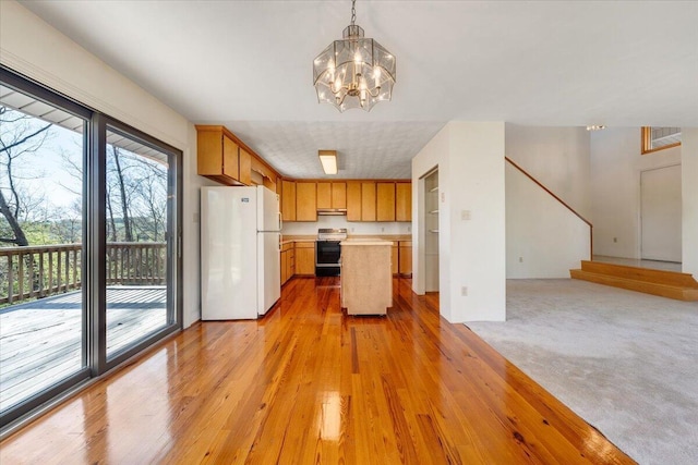 kitchen featuring an inviting chandelier, open floor plan, light countertops, freestanding refrigerator, and stove