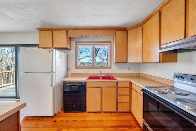 kitchen featuring light countertops, freestanding refrigerator, range with electric cooktop, dishwasher, and a sink