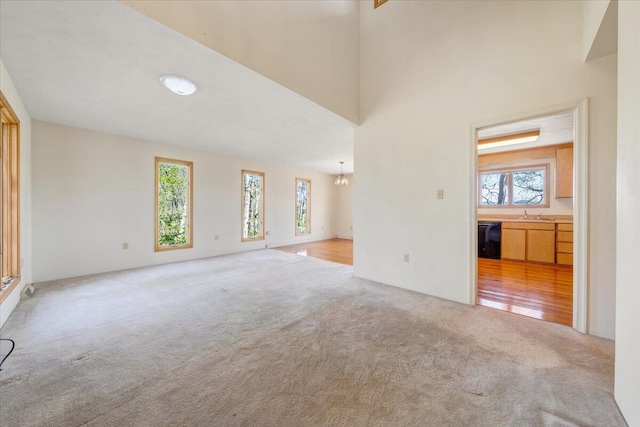 unfurnished living room featuring a chandelier, carpet flooring, and a sink