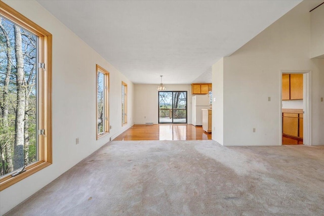 unfurnished living room featuring a chandelier and light carpet