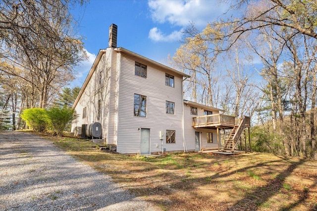 back of property with stairs, a wooden deck, and a chimney