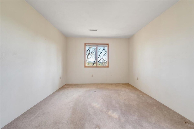 spare room featuring visible vents and light colored carpet