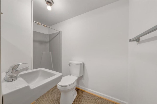 bathroom with a sink, toilet, baseboards, and walk in shower