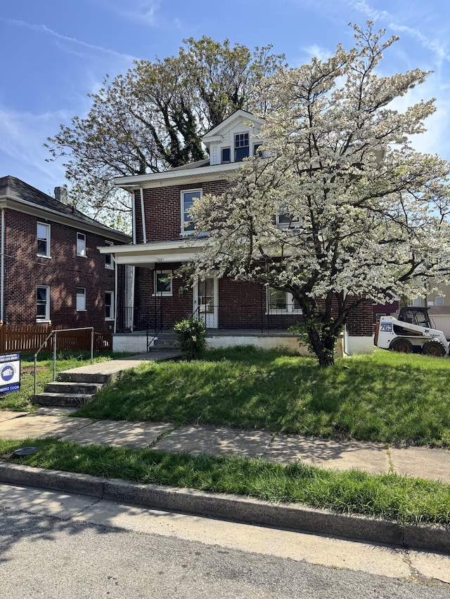traditional style home featuring brick siding, a front lawn, and covered porch
