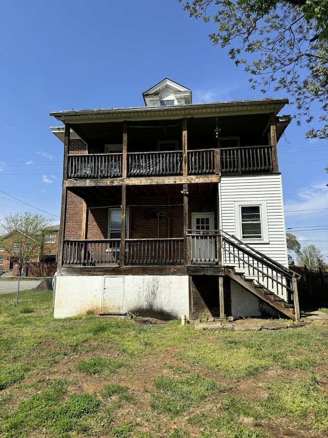 back of house with fence, a balcony, a lawn, and stairs