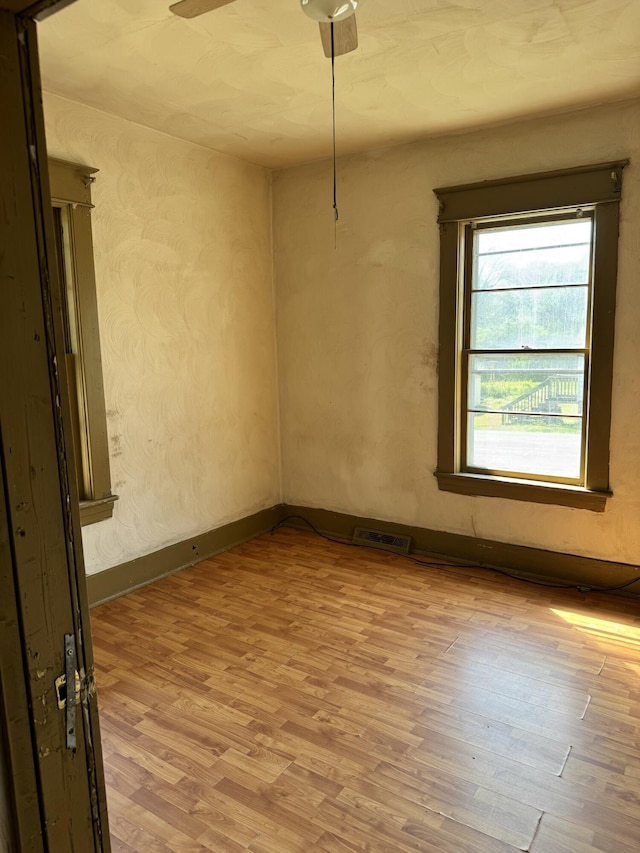 spare room with light wood-style floors, baseboards, a ceiling fan, and visible vents