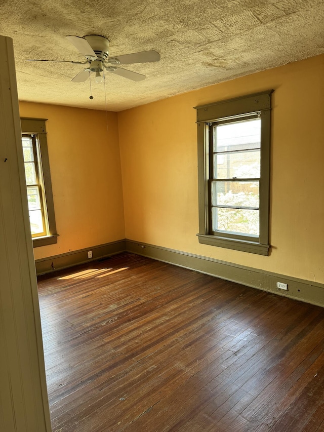 empty room featuring a wealth of natural light, wood-type flooring, a textured ceiling, and a ceiling fan