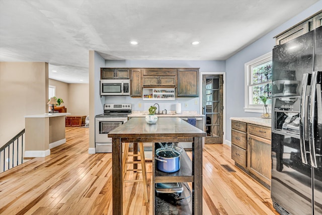 kitchen with baseboards, light countertops, light wood-type flooring, recessed lighting, and stainless steel appliances