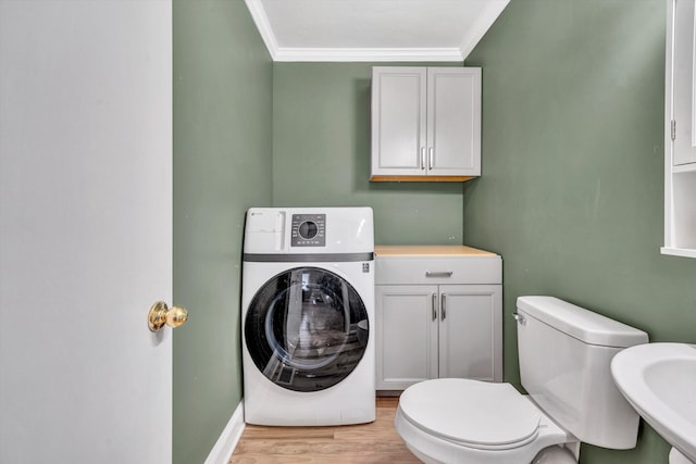 bathroom with a sink, ornamental molding, toilet, wood finished floors, and washer / dryer
