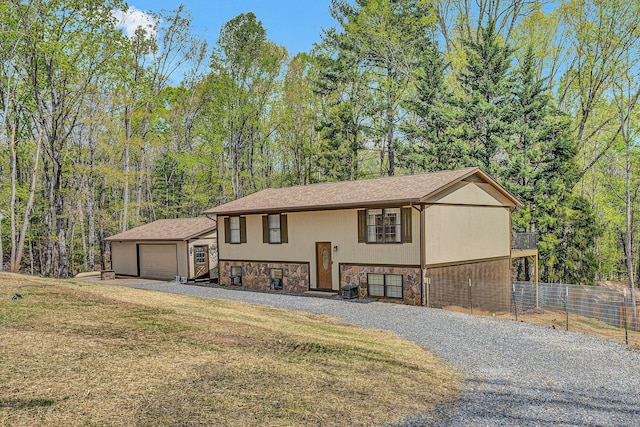 view of front of home with an outdoor structure, fence, gravel driveway, stone siding, and a garage