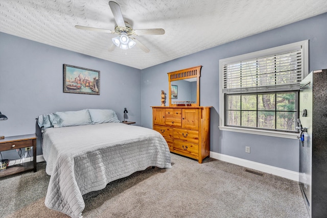 carpeted bedroom featuring visible vents, baseboards, ceiling fan, and a textured ceiling