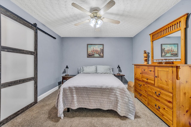 bedroom with carpet floors, a ceiling fan, a barn door, and a textured ceiling