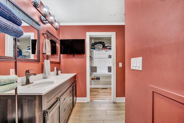 bathroom with wood finished floors, double vanity, a sink, and baseboards