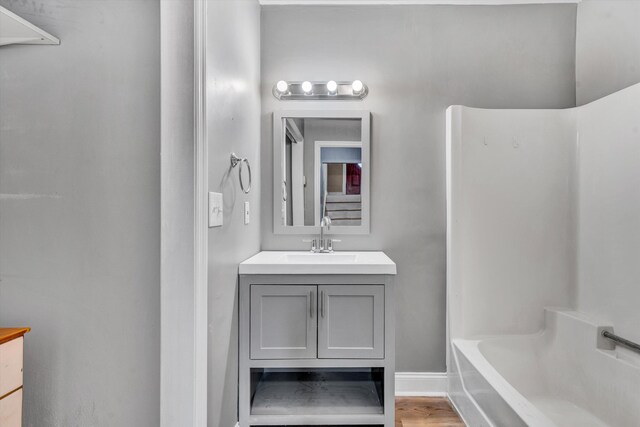 full bathroom featuring wood finished floors, vanity, and baseboards