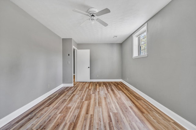 unfurnished room with ceiling fan, light wood finished floors, and baseboards
