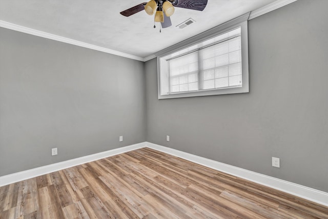 empty room with baseboards, ornamental molding, a ceiling fan, visible vents, and wood finished floors