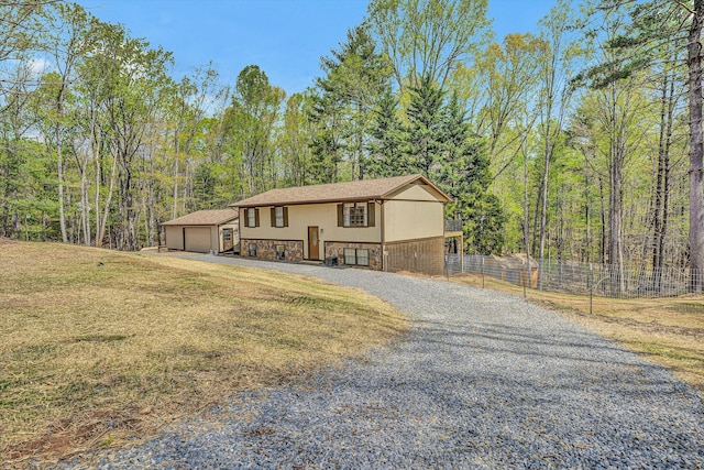 bi-level home with an outdoor structure, stone siding, a front yard, a garage, and fence