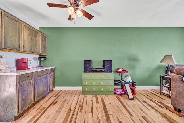 interior space with baseboards, a ceiling fan, and light wood-style floors