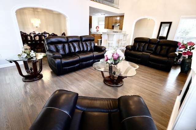 living room featuring arched walkways, a notable chandelier, and wood finished floors