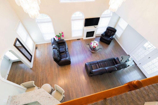 living area with a fireplace, wood finished floors, a healthy amount of sunlight, and an inviting chandelier