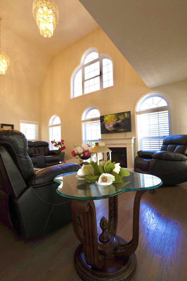 living room with a chandelier, wood finished floors, a fireplace, and a wealth of natural light