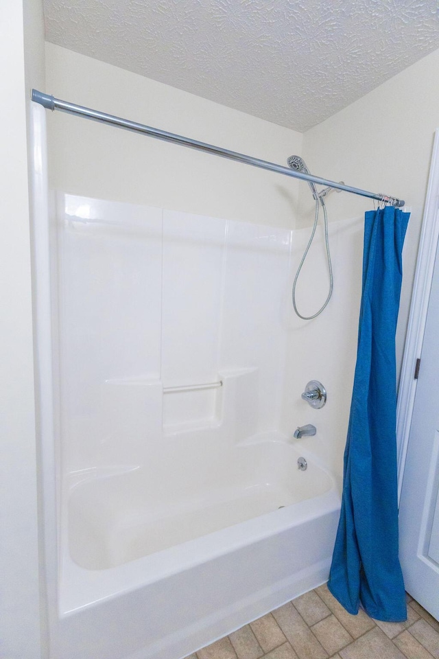 full bathroom featuring a textured ceiling and shower / bathtub combination with curtain