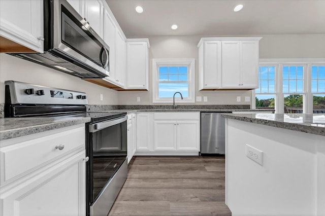 kitchen with a sink, appliances with stainless steel finishes, white cabinets, and recessed lighting