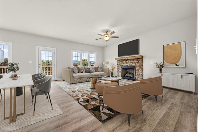 living room featuring a ceiling fan, light wood-style flooring, and a fireplace