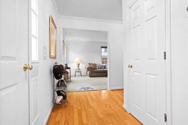 hall featuring ornamental molding, baseboards, and wood finished floors