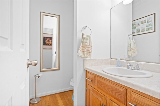 bathroom featuring wood finished floors, toilet, baseboards, and vanity