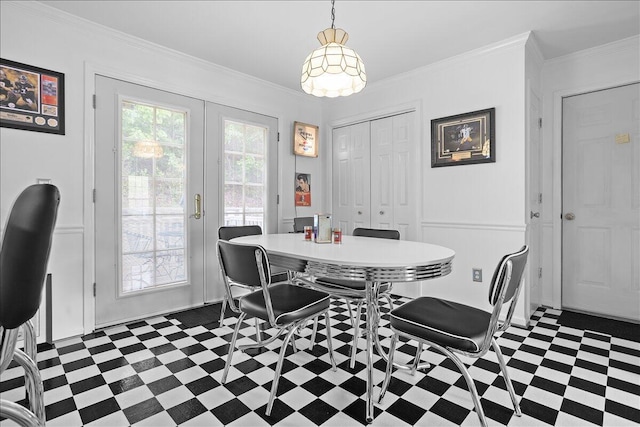 dining area with dark flooring, french doors, ornamental molding, and a decorative wall