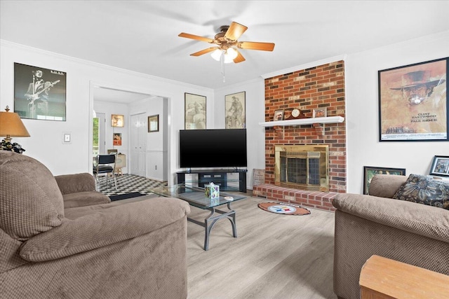living room with ceiling fan, crown molding, wood finished floors, and a fireplace