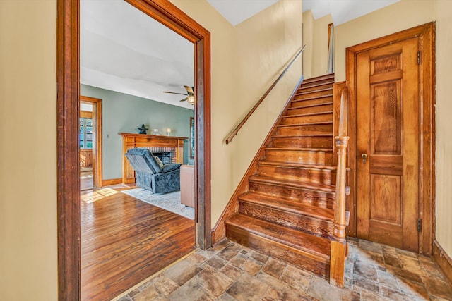 1112 Highland Rd, Salem, VA 24153 - stairs featuring a ceiling fan, stone finish floors, a brick fireplace, and baseboards