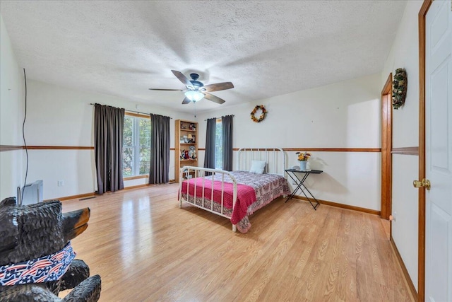 bedroom with baseboards, a ceiling fan, a textured ceiling, and wood finished floors