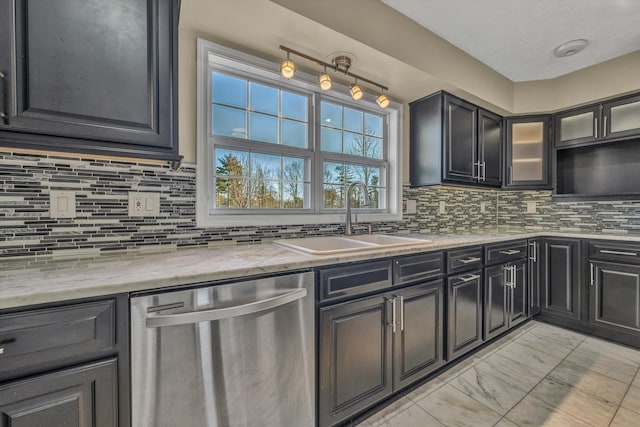 kitchen with stainless steel dishwasher, a sink, backsplash, and light stone counters