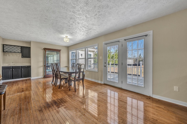 dining area with baseboards, hardwood / wood-style floors, and a textured ceiling
