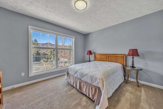 carpeted bedroom featuring visible vents, baseboards, and a textured ceiling