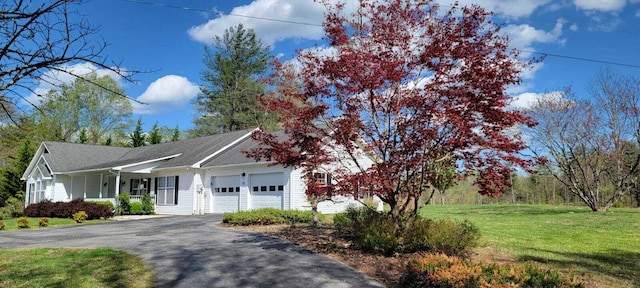 view of home's exterior with an attached garage, a lawn, driveway, and covered porch