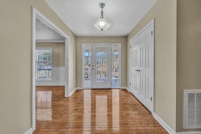 entrance foyer featuring a textured ceiling, hardwood / wood-style floors, visible vents, and baseboards
