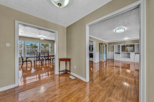spare room featuring baseboards, a textured ceiling, hardwood / wood-style flooring, and visible vents