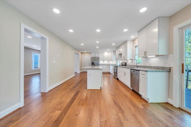 kitchen with backsplash, a sink, white cabinetry, and appliances with stainless steel finishes