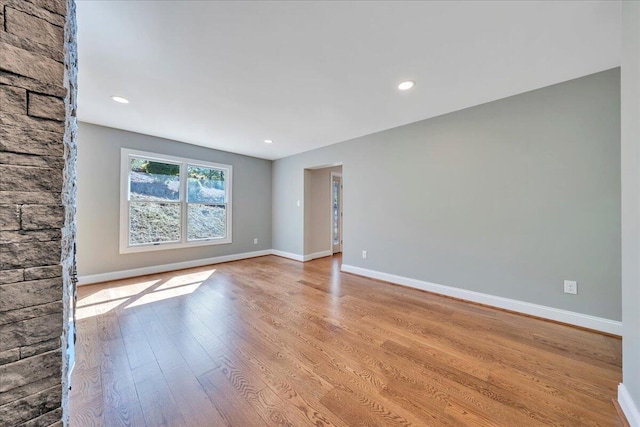 unfurnished living room with recessed lighting, wood finished floors, and baseboards