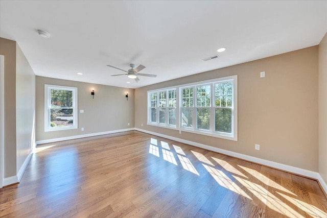 empty room featuring baseboards, visible vents, recessed lighting, a ceiling fan, and wood finished floors