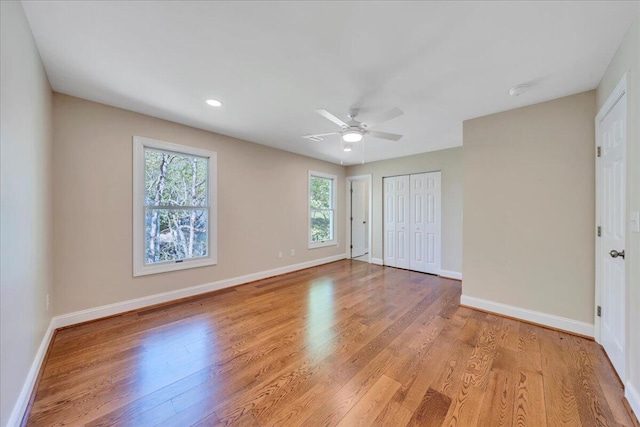 unfurnished bedroom featuring a closet, baseboards, a ceiling fan, and light wood-type flooring