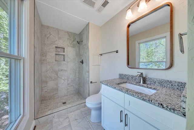 bathroom with vanity, marble finish floor, a tile shower, toilet, and visible vents